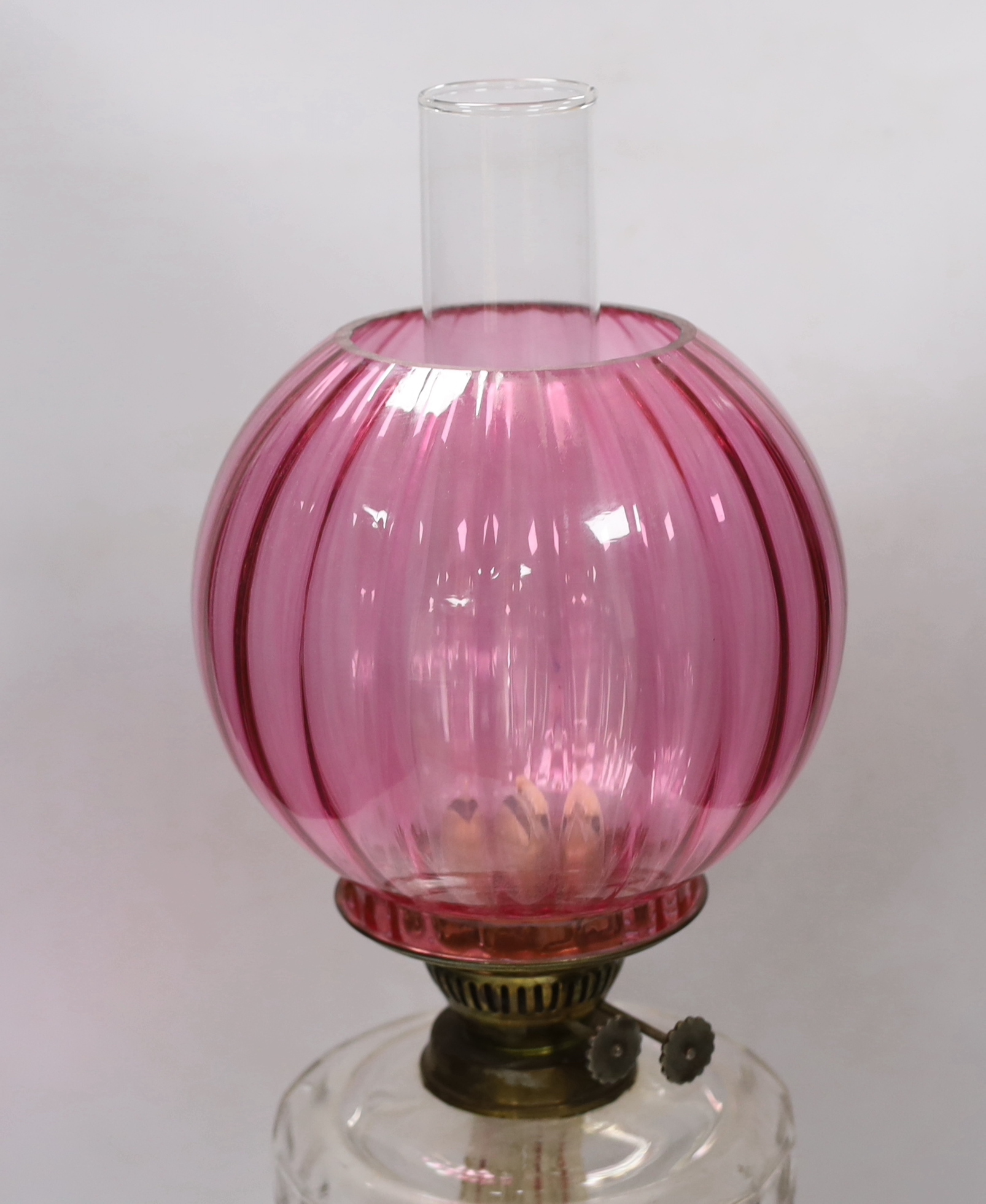 A Victorian brass based oil lamp, with cranberry glass shade, 58cm high